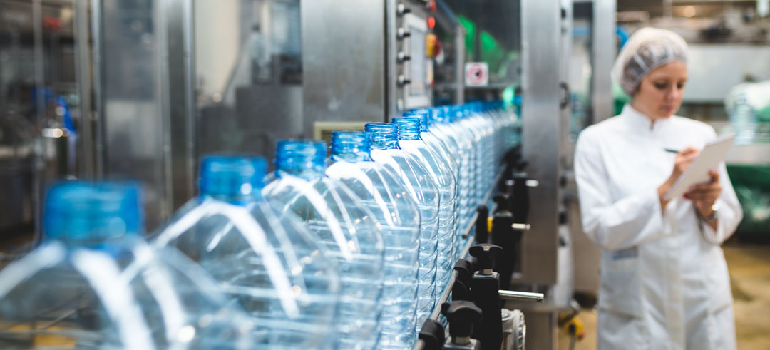 Mujer apuntado en un documento la producción de botellas de agua