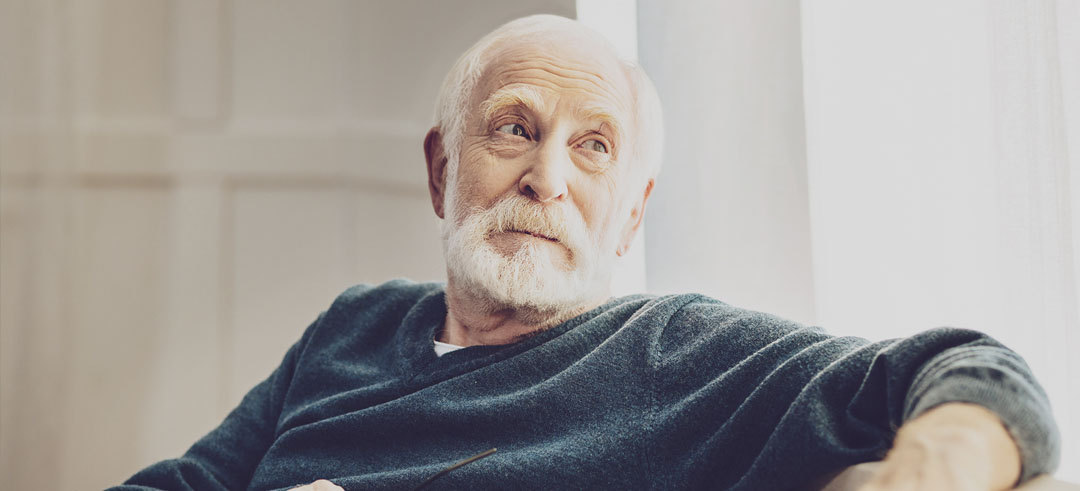 Hombre adulto tranquilo sentado mientras por la ventana