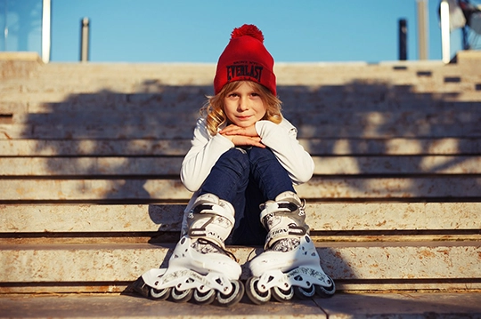 Niño sentado en unas escaleras con patines puestos en sus pies