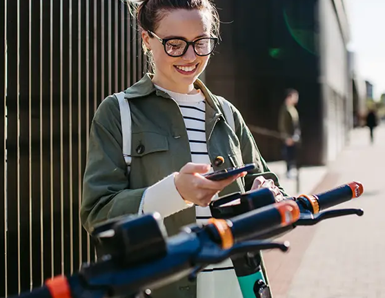 Chica joven colocando el móvil en un patinetes eléctricos para circular