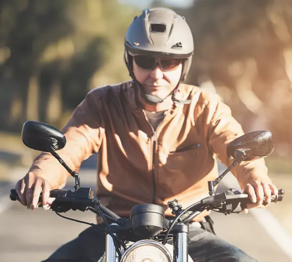 primer plano de una moto custom y un conductor con chaqueta de cuero